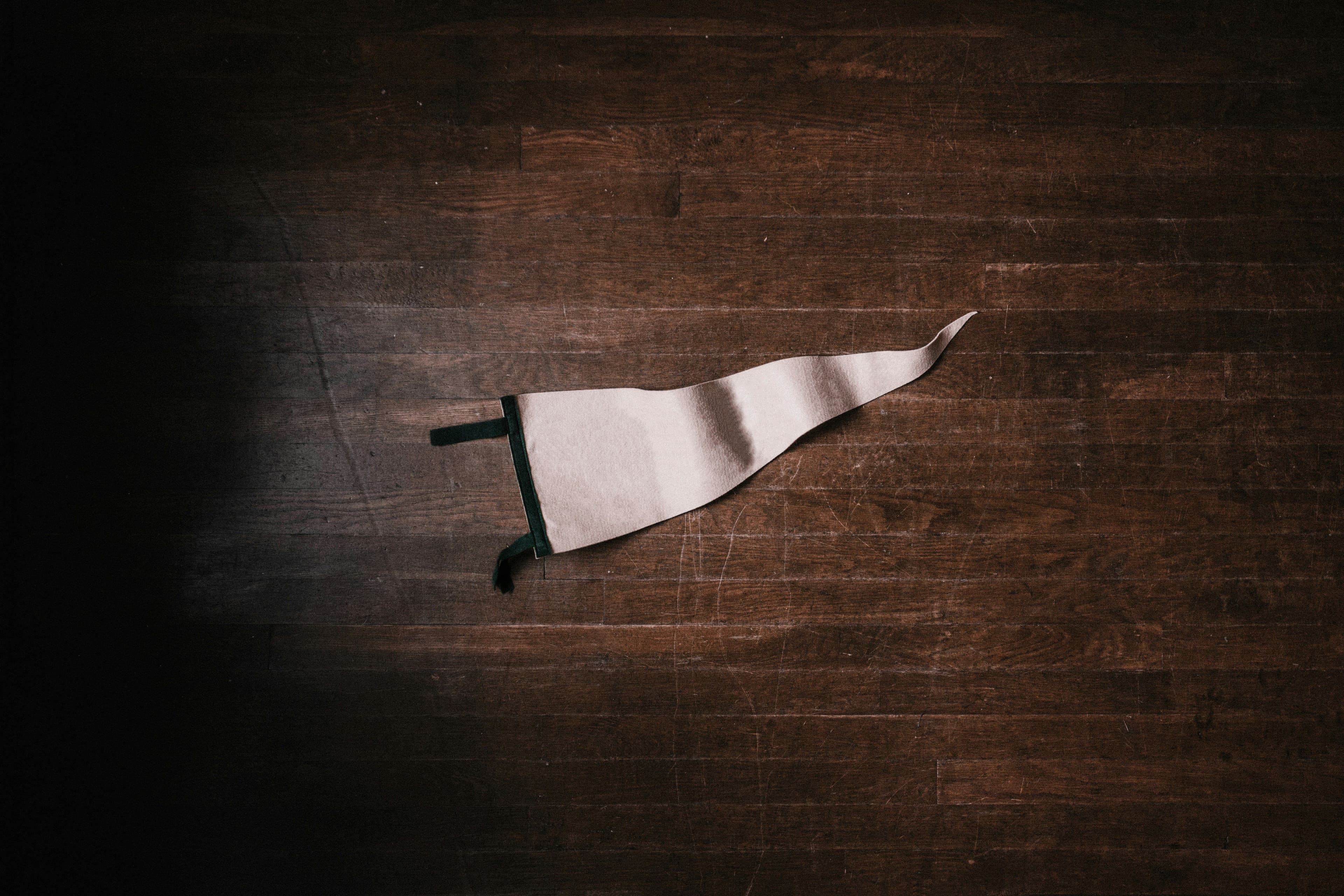 White triangular flag thrown on a brown wooden floor in a spotlight